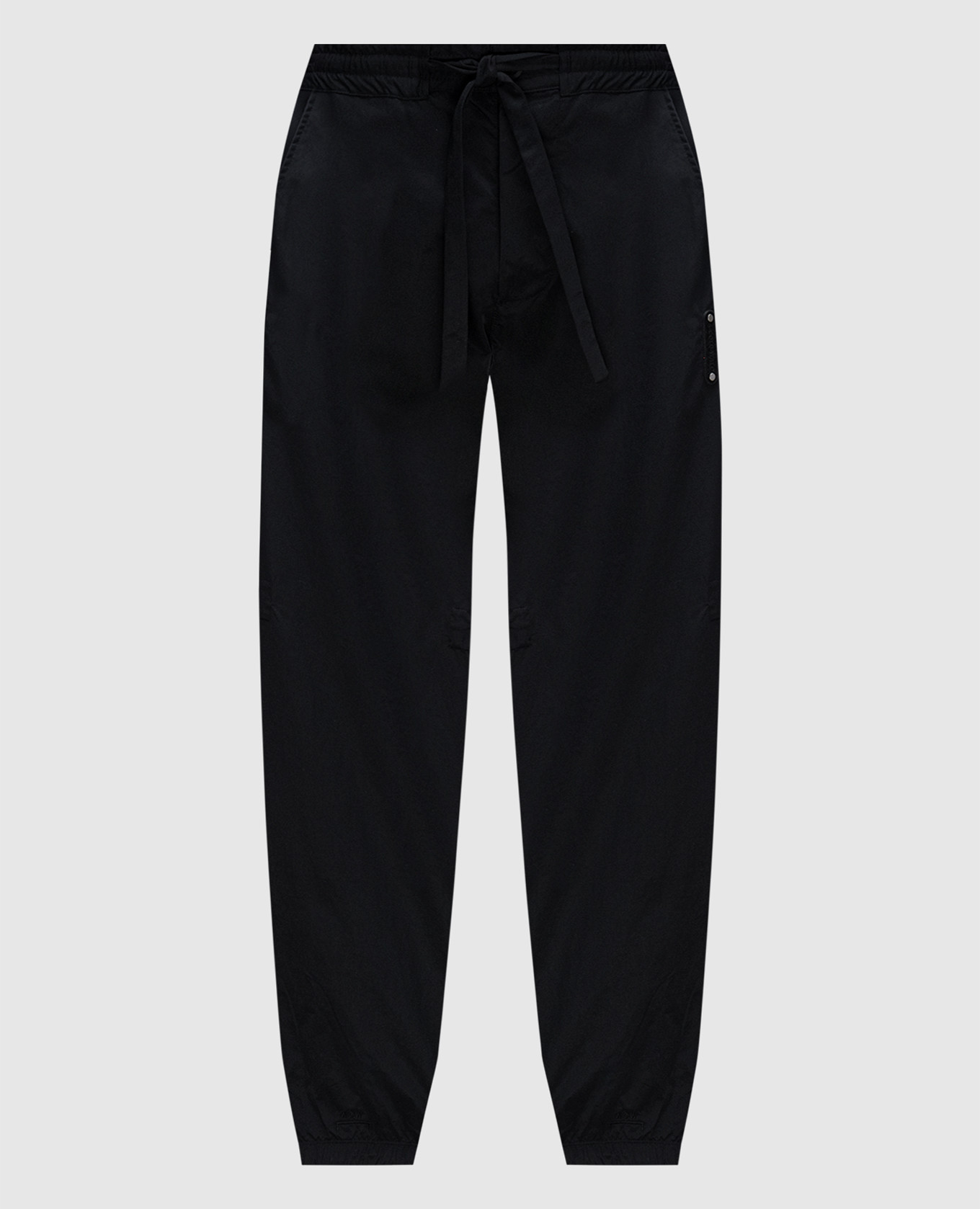 Black joggers with logo patch a cold wall